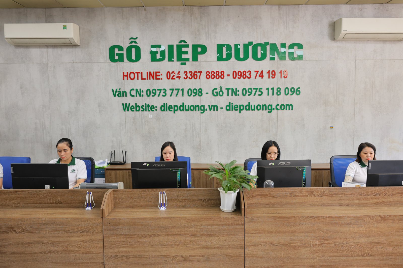 Bốn nhân viên Điệp Dương làm việc bên máy tính tại quầy giao dịch, tường phía sau in tên công ty và số hotline